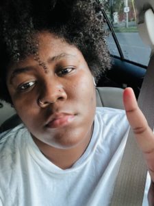 Photo of Ashleigh in a car raising one finger