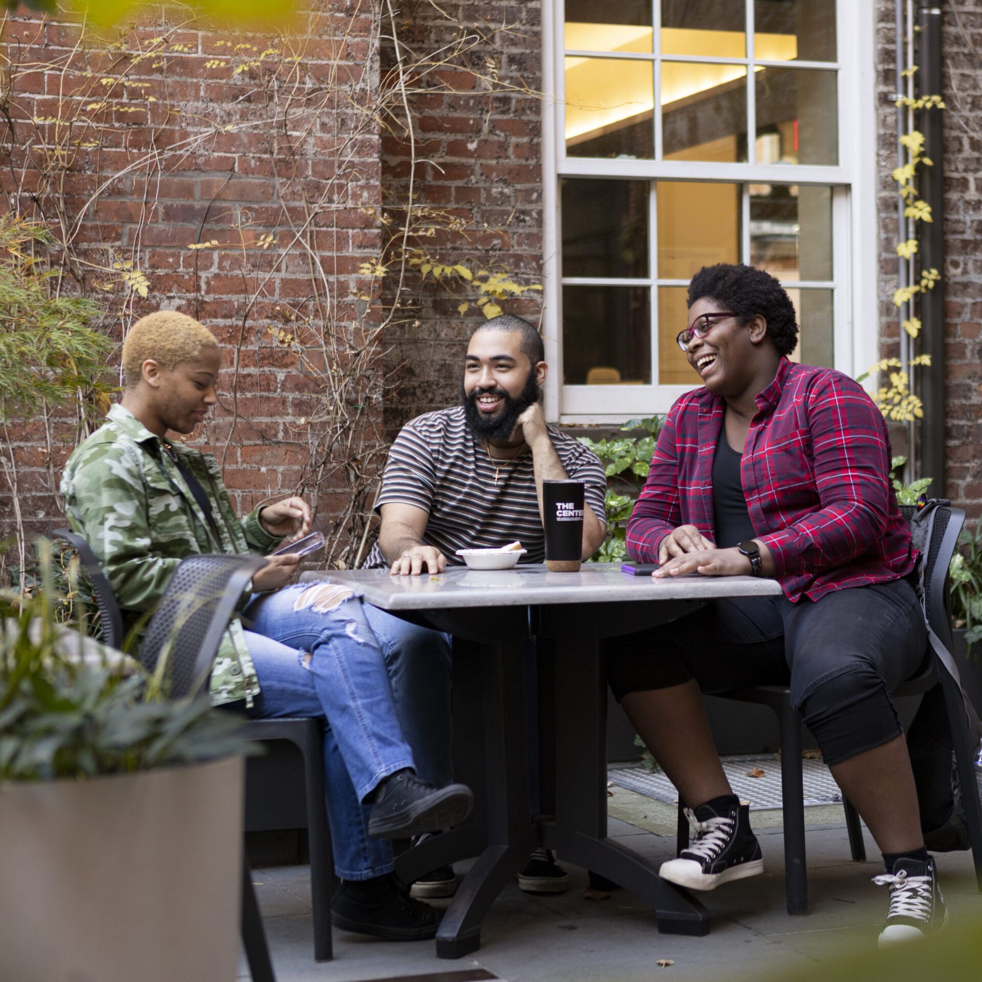 Three people sitting around a table talking and laughing.