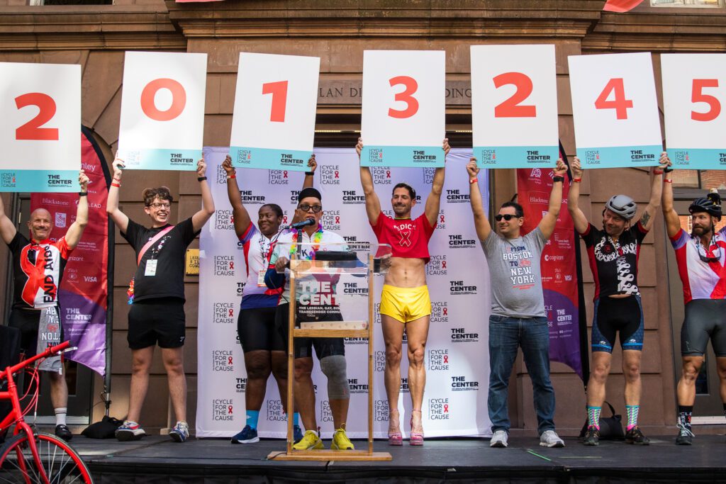 People stand on a small stage holding large number cards 2013245