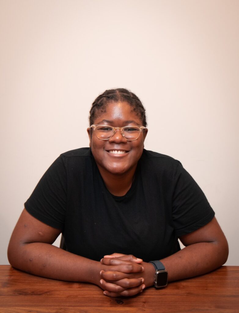 Black person wearing glasses and smiling into