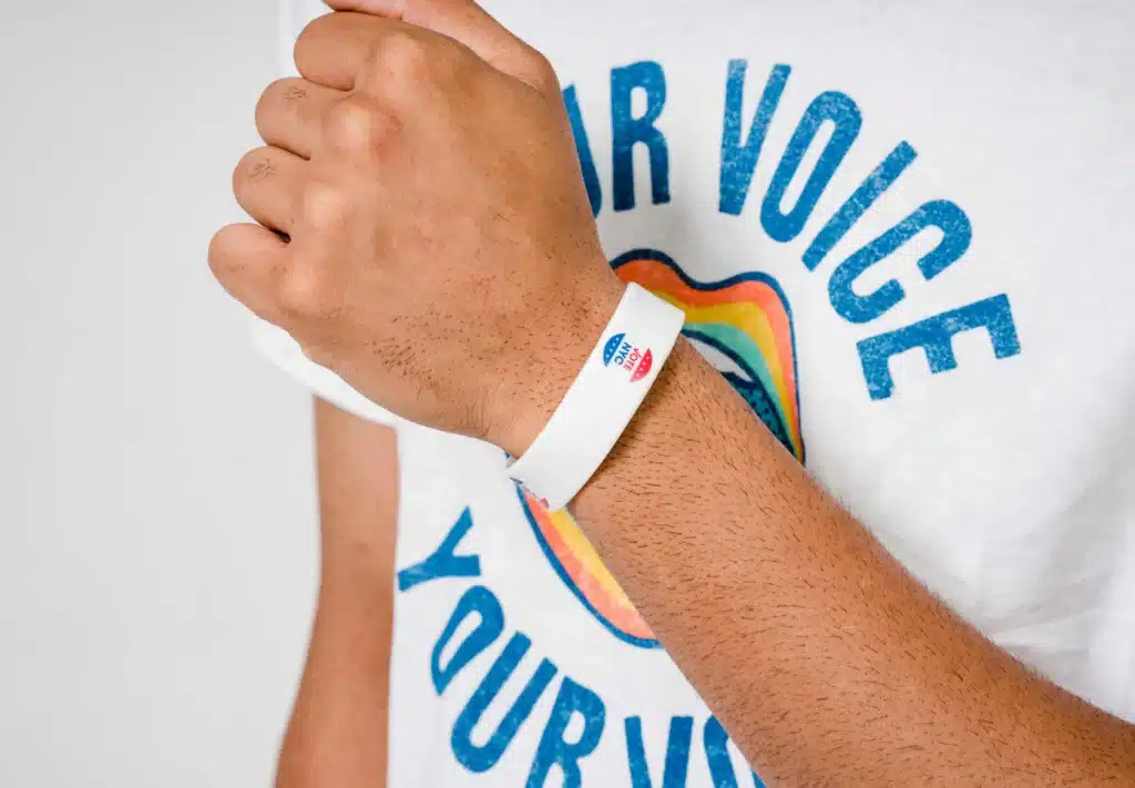 close up image of a person wearing a your voice your vote t-shirt their arm is in front of their chest and they are wearing a Vote NYC bracelet