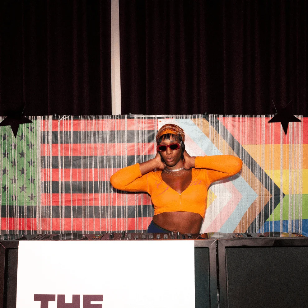 DJ at Juneteenth Block Party behind Pride flag